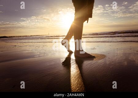 Netherlands, Cadzand-Bad, legs of teenage boy walking on the beach at twilight Stock Photo