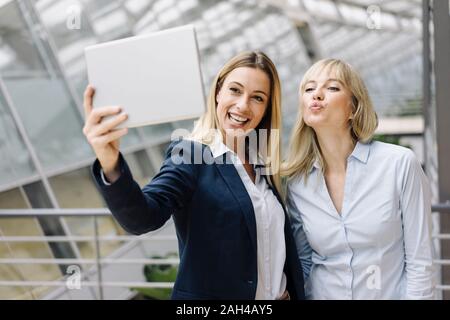 Two happy young businesswomen using a tablet in office Stock Photo