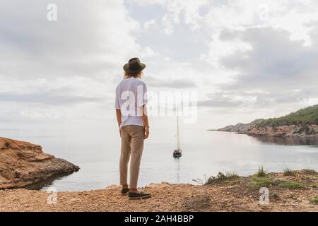 Back view of young man standing in front of the sea looking at view, Ibiza, Balearic Islands, Spain Stock Photo