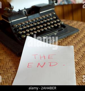 Vinatge typewriter and a blank sheet with written words The End on the table Stock Photo