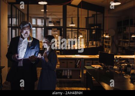 Happy senior buisinessman and girl with hot-air balloon and shining tablet in office Stock Photo