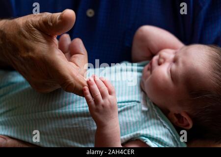 Sleeping newborn baby holding grandfathers finger Stock Photo