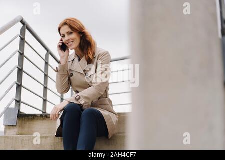 Businesswoman sitting on stairs, talking on the phone Stock Photo