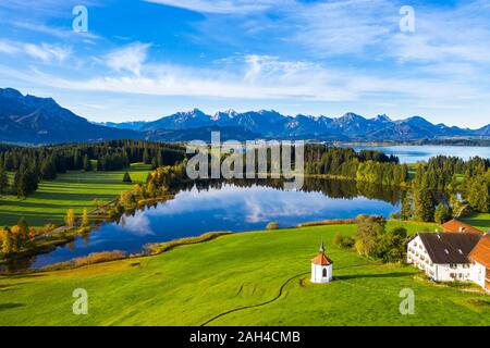 Germany, Bavaria, Halblech, Aerial view of small chapel, farmhouse and Hegratsrieder See lake in Tannheim Mountains Stock Photo