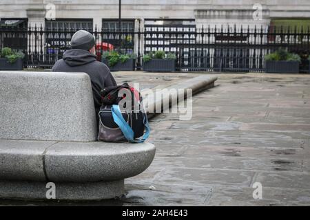 Central London, London, 24th Dec 2019. The area around St Martin in the Fields has several homeless charity facilities, including a soup kitchen and 'The Connection' at St Martin's. A man quietly sits outside the church. Christmas Eve.The number of households newly homeless has risen over the last 12 months, and in London, the growing problem is particularly visible with the number of rough sleepers having surged to new highs. Credit: Imageplotter/Alamy Live News Stock Photo