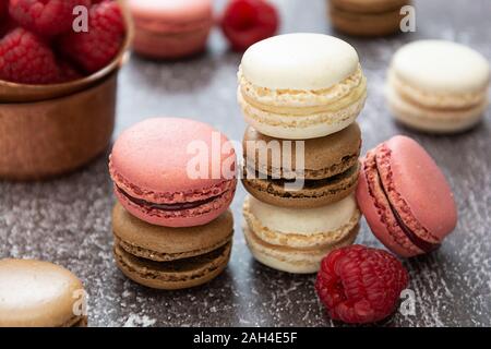 Heap of macarons isolated on dark background. Healthy cake dessert made from almond flour. Raspberry macaroons cookies. Stock Photo