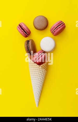 Macarons cakes. Stil life photo of waffle cone with macaroons on yellow ...