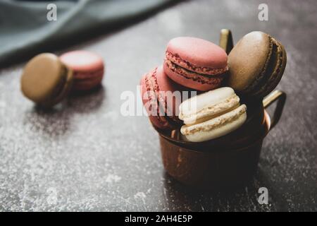 Macarons isolated on dark background. Healthy cake dessert made from almond flour. Vintage dark toned image. Stock Photo