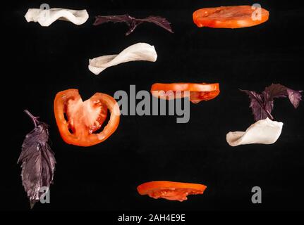 slices of tomato, mozzarella cheese and basil flying on black background. caprese Stock Photo