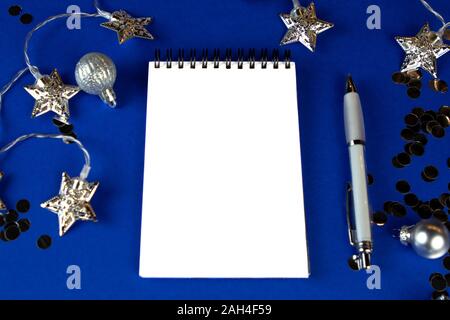 Christmas, winter composition. Notebook with isolated white page, open diary, sketch book mock-up scene on blue surface. Stock Photo