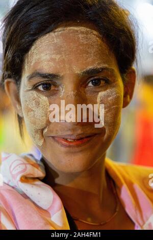 Portrait of local woman with thanaka on her face, in Yangon, Myanmar. Thanaka is cosmetic paste made from ground bark Stock Photo