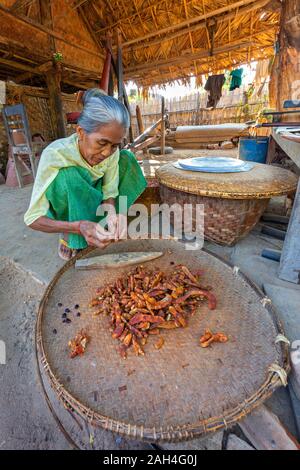 Local elderly woman peeling tamarind in Bagan, Myanmar Stock Photo