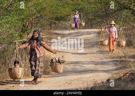 Women with their basket with one of them carrying her child and wood in the basket, in Bagan, Myanmar Stock Photo