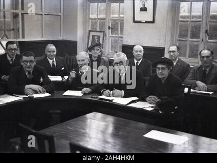 1950s, historical, local government, council members attending a meeting, sitting at curved wooden desk, with the minutes or the agenda of the meeting infront of them, England, UK. Stock Photo