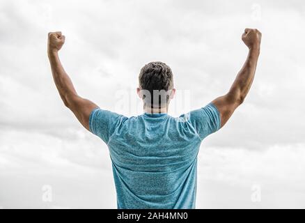 Victory and success. Champion winner. Future opportunity. Leadership and competition. Future concept. Looking forward in future. Strong muscular body feeling powerful rear view. Successful athlete. Stock Photo