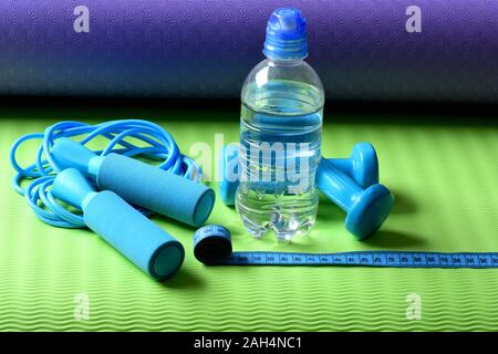 https://l450v.alamy.com/450v/2ah4nc1/workout-and-refreshment-concept-bottle-or-water-near-jump-rope-and-barbells-on-yoga-mat-skipping-rope-cyan-dumbbells-and-tape-near-water-bottle-on-green-and-purple-background-sports-and-health-2ah4nc1.jpg