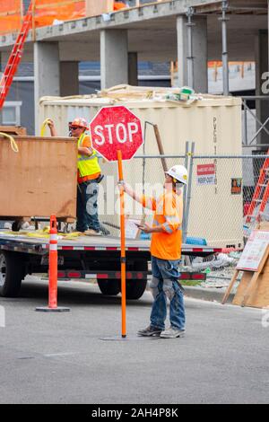 construction worker on cell phone with stop go board in Seattle Washington State USA Stock Photo