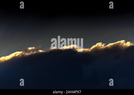 Bank of cloud with sunset highlights against dark sky Stock Photo