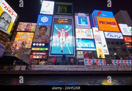 OSAKA, JAPAN - OCTOBER 14, 2019:  The bright and flashy billboards along the Dotonbori canal with the symbol of the city, the Glico Running Man at nig Stock Photo