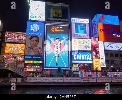 OSAKA, JAPAN - OCTOBER 14, 2019:  The bright and flashy billboards along the Dotonbori canal with the symbol of the city, the Glico Running Man at nig Stock Photo