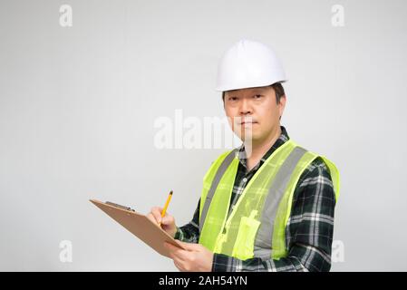 A middle-aged Asian worker checking something with a checklist in his hand. Stock Photo