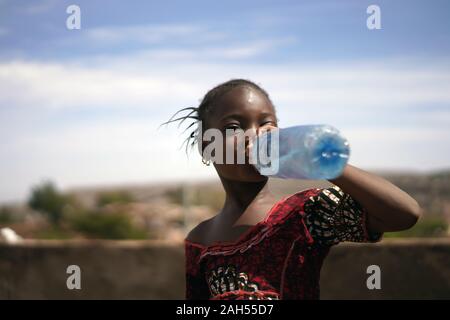 Portrait Of a Small African Girl Greedily Rinking from a Water Bottle Stock Photo
