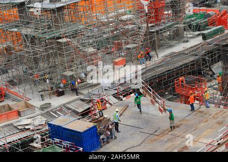 Bangkok, Thailand - December 23, 2019 : Closeup steel frame being moved by tower crane while two workers walking and holding it  at  construction site Stock Photo