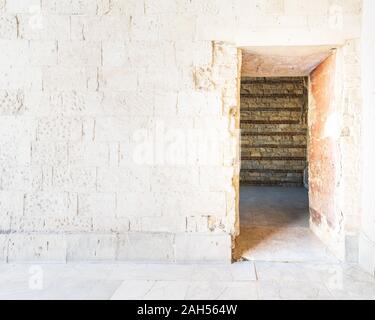 Aged abandoned building with weathered arch and crumbling walls on town street on sunny day Stock Photo