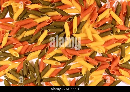 Three-colored obliquely cut tubes of pene paste, scattered like a background. Stock Photo