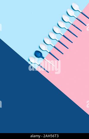 Concept of white plastic spoons on tricolor blue pink background. Flat lay, top view, copy space. Stock Photo
