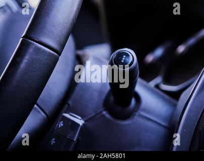 View of the turn signal lever and a part of the steering wheel in the front interior of a car Stock Photo