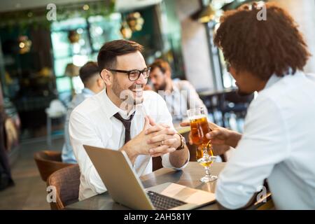 Two businessmen working on the go on a laptop together in a cafe. Stock Photo