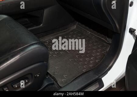 Dirty car floor mats of black rubber under passenger seat in the workshop for the detailing vehicle before dry cleaning. Auto service industry. Interi Stock Photo