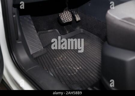 Dirty car floor mats of black rubber with gas pedals and brakes in the workshop for the detailing vehicle before dry cleaning. Auto service industry. Stock Photo