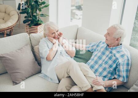 Above high angle view of her she his he two nice attractive cheerful, cheery positive spouses sitting on cosy divan having fun time in light white int Stock Photo