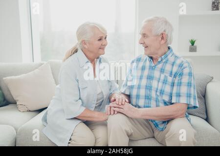 Portrait of her she his he two nice attractive lovely sweet tender gentle cheerful, spouses holding hands sitting on divan spending romantic time in l Stock Photo