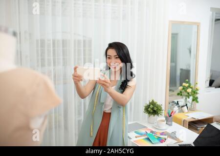 Beautiful Asian fashion designer taking a picture of new product Stock Photo