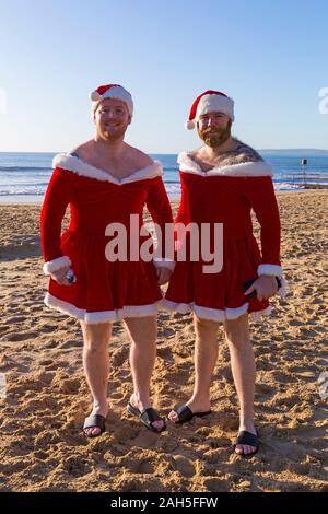 Boscombe, Bournemouth, Dorset, UK. Christmas Day 25th December 2019. Brave volunteers plunge into the sea for a swim or dip on a lovely sunny day, for the annual charity White Christmas Dip, the largest Christmas Dip in the UK, dressed in fancy dress costumes and raising money for Macmillan Caring Locally at Christchurch, a Specialist Palliative Care Unit for patients in the local community. Over a thousand take part in the event which has become a popular tradition for many before their Christmas lunch. A couple of Santa Babes! Credit: Carolyn Jenkins/Alamy Live News Stock Photo