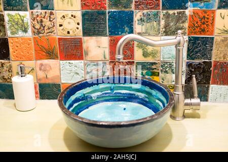 Photos of the interior design of the bathroom. Beautiful ceramic washbasin with colored ceramic tiles. Stock Photo