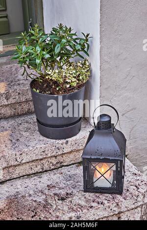 Large street lanterns with burning candles on terrace of cozy cafe on snowy city street. Cozy moments of wintertime concept Stock Photo