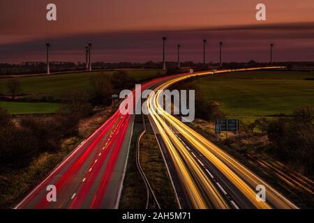 Light trails of vehicles on a busy dual carriageway at nightfall. Stock Photo