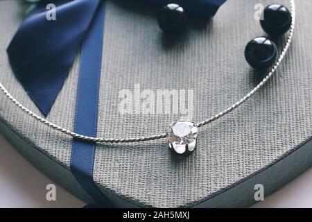 Crown for real queen. Jewelry composition on interior background and giftbox in blue color. Chainlet with tender gemstone for gift, marrying, New Year Stock Photo