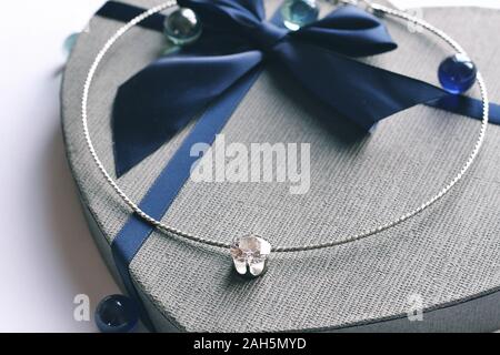 Cold love and crown. Jewelry composition on interior background and giftbox in blue color. Chainlet with tender gemstone for gift, marrying, New Year Stock Photo