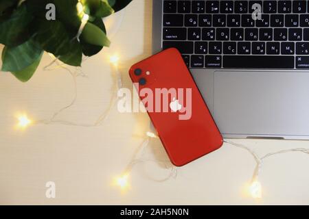 Kyiv, Ukraine. Modern MacBook Laptop with retina computer and red Iphone 11 on white in interior with domestic plants, lights, bokeh. Technologies, on Stock Photo