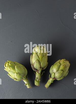 three fresh artichokes on black background. isolated from the background, copy space Stock Photo