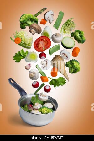 Fresh vegetables flying, isolated on orange background. Stock Photo