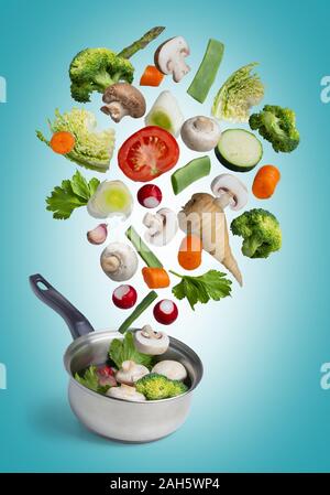 Fresh vegetables flying in a pot, isolated on blue background. Stock Photo