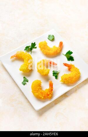 Deep fried breaded prawn on white plate over light stone background. Stock Photo