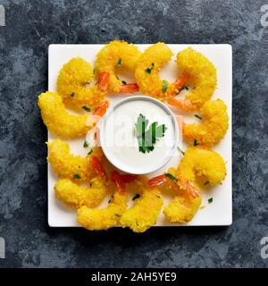 Fried shrimps with sauce on white plate over blue stone background. Top view, flat lay Stock Photo