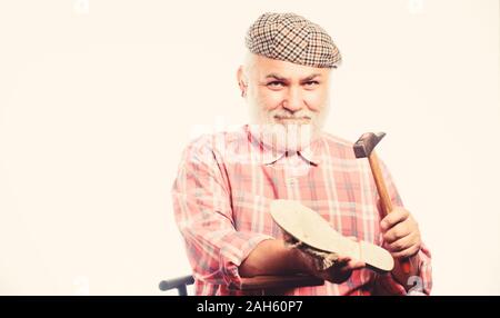 Fits perfect. shoemaker at work. mature shoemaker in workshop make shoes. Cobbler workmanship. shoemaker working with leather textile and hammer at workshop. retro man repair shoes with hammer. Stock Photo